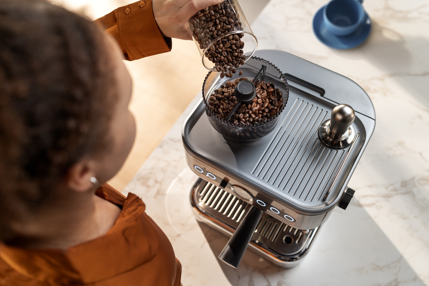 Devojka sipa kafu u zrnu u posudu na aparatu Philips Barista Brew